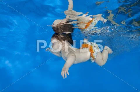 4 months infant learning to swim underwater in waterbaby class in the pool Stock Photos