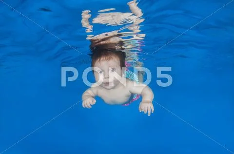 4 months infant learning to swim underwater in waterbaby class in the pool Stock Photos