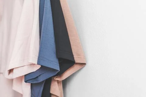 4 multi-colored t-shirts, sleeves close-up against a white wall, space for te Stock Photos