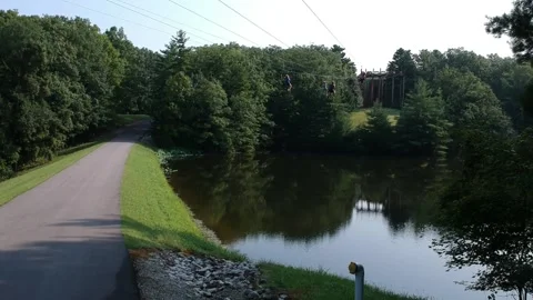 4 people zip lining over small lake Vídeos de archivo 133971469