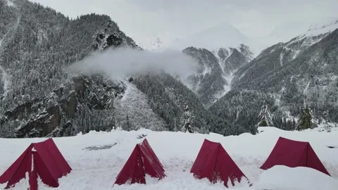 4 red colored camping tent in the snow. snow covered mountains trees in backg Video stock 157664900