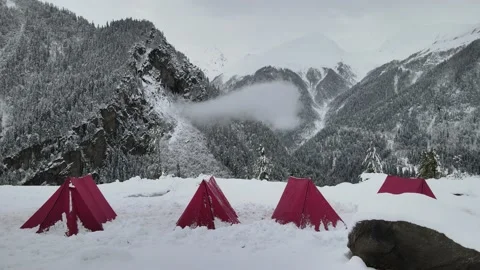 4 red colored camping tent in the snow. snow covered mountains trees white sk Video stock 157664916