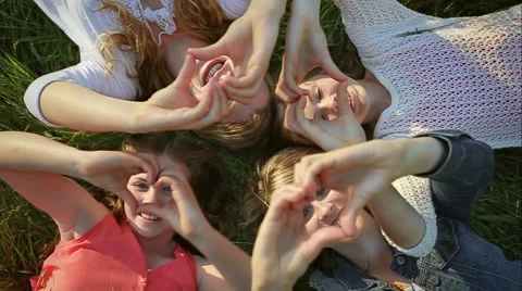 4 Sisters Lay In Grass, Hold Up Hands To Make Heart Shapes, They Smile Video stock 42906776