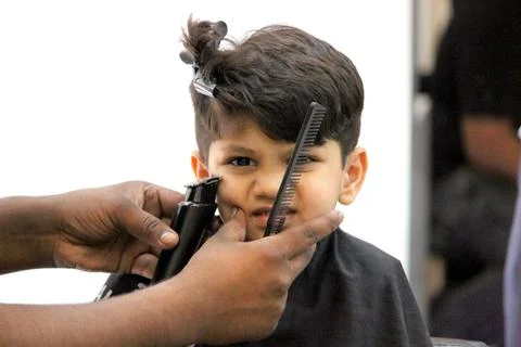 4 year old boy is getting his haircut done at barber shop Stock Photos