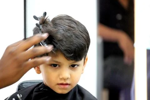 4 year old boy is getting his haircut done at barber shop Stock Photos