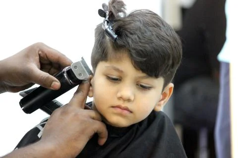 4 year old boy is getting his haircut done at barber shop Stock Photos