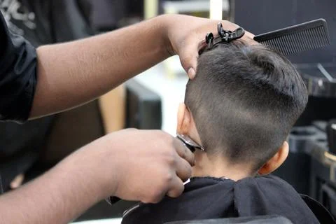 4 year old boy is getting his haircut done at barber shop Stock Photos