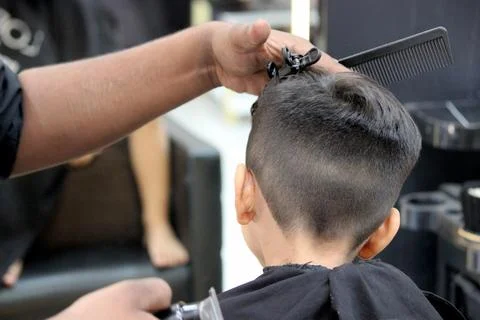 4 year old boy is getting his haircut done at barber shop Stock Photos