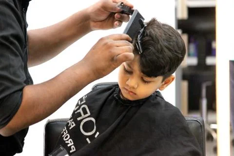 4 year old boy is getting his haircut done at barber shop Stock Photos