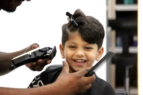 4 year old boy is getting his haircut done at barber shop Stock Photos