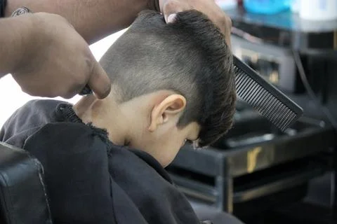 4 year old boy is getting his haircut done at barber shop Stock Photos