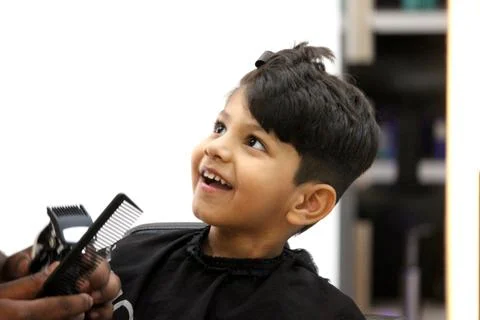 4 year old boy is getting his haircut done at barber shop Stock Photos