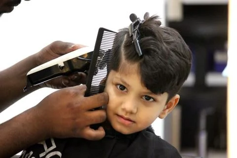 4 year old boy is getting his haircut done at barber shop Stock Photos
