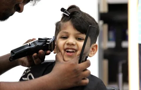 4 year old boy is getting his haircut done at barber shop Stock Photos