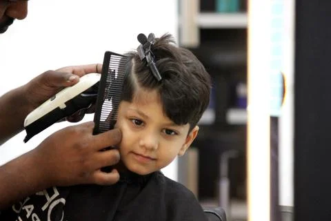 4 year old boy is getting his haircut done at barber shop Stock Photos