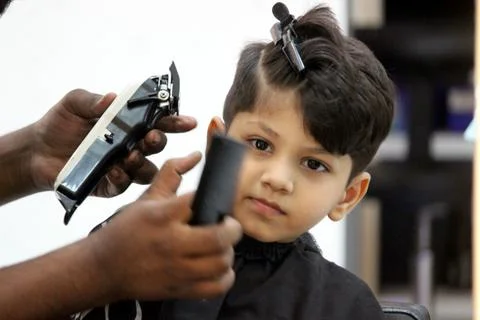 4 year old boy is getting his haircut done at barber shop Stock Photos