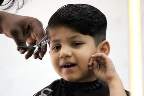 4 year old boy is getting his haircut done at barber shop Stock Photos