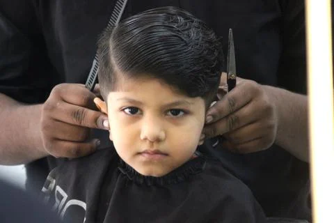 4 year old boy is getting his haircut done at barber shop Stock Photos