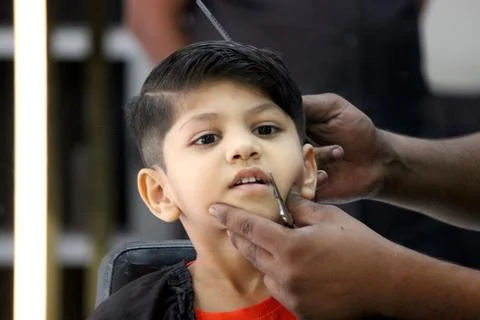 4 year old boy is getting his haircut done at barber shop Stock Photos