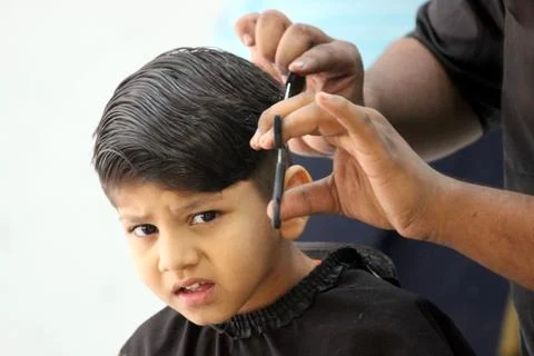 4 year old boy is getting his haircut done at barber shop Stock Photos