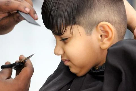 4 year old boy is getting his haircut done at barber shop Stock Photos