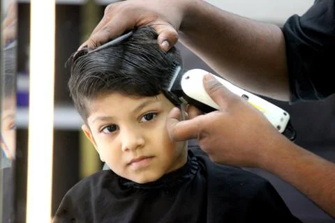 4 year old boy is getting his haircut done at barber shop Stock Photos