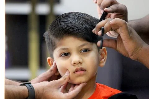 4 year old boy is getting his haircut done at barber shop Stock Photos