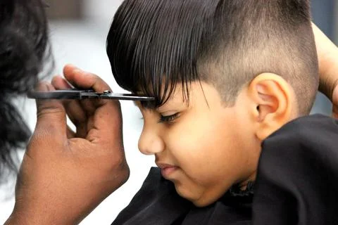 4 year old boy is getting his haircut done at barber shop Stock Photos