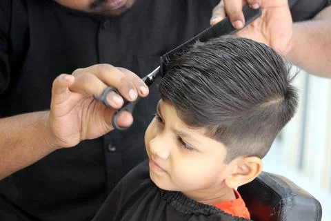 4 year old boy is getting his haircut done at barber shop Stock Photos