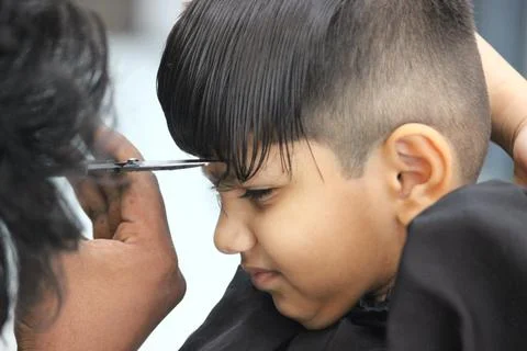 4 year old boy is getting his haircut done at barber shop Stock Photos