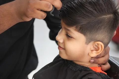 4 year old boy is getting his haircut done at barber shop Stock Photos
