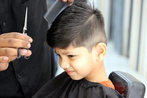 4 year old boy is getting his haircut done at barber shop Stock Photos