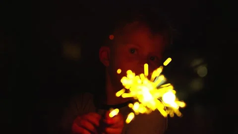 4 year old boy holds sparkler towards camera during late night celebration Stock Footage 248085906
