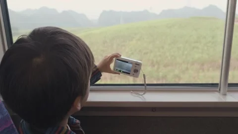 4-Year-Old Boy Taking Photos on Train Journey Through Rural South China Stock Footage 329635109