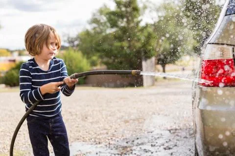 4 year old boy washing a car in the parking lot Stock Photos