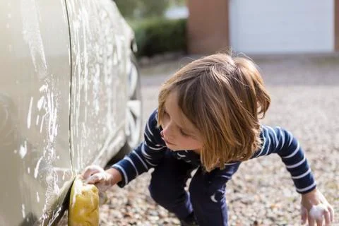 4 year old boy washing a car in the parking lot Stock Photos