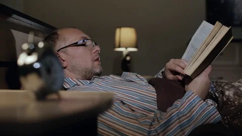 A 40-year-old man reading a book before going to bed Video stock 84740894