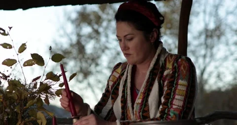 40s woman wearing patterned jacket heat end of red candle to put in candlestick Stock Footage 165140528