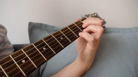 45 Young man hands play the guitar sitting on couch at home closeup Stock Footage 104661342