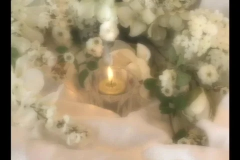 4510 Single lite candle on white silk and flowers Stock Footage 792960