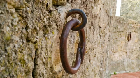48662 Rusted Metal Ring Embedded in Stone Wall Showcasing Weathered Texture.. Stock Footage 304169445