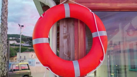 48693 Bright Orange Life Ring Displayed Outside a Coastal Building During S.. Stock Footage 304169901