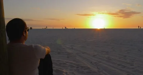 490 Ots of a Man Sitting on a beach people watching during the sunset Stock-Footage 134546669