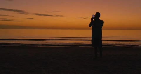 495 Man taking a picture of the sunset at the beach Stock-Footage 134547697