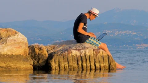 4G, 5G connection background. Guy working near the rocks and the sea. Video stock 117099733