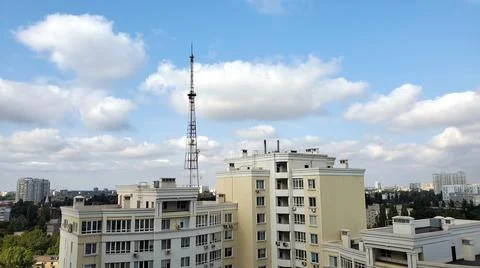 4G Tower and rooftop of modern yellow building condo against white clouds in Stock Photos