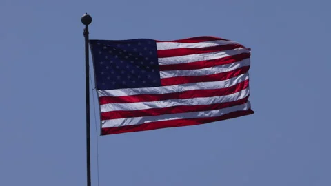 4K 120 fps slow motion long shot of an American flag waving in a clear blue sky Video stock 195281457