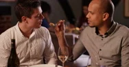 4K 2 Men Enjoying Dinner In A Restaurant, Man Offers Friend A Taste Of His Meal Stock Footage