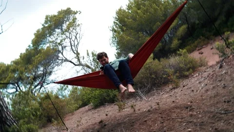 4K 24fps video. Camera do a vortex while approaching to a young man lying in  Video stock 132516528