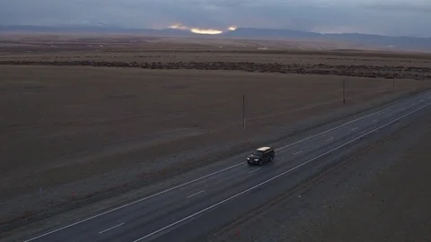 4k Aerial: black suv car driving along the empty countryside road at sunset Stock Footage